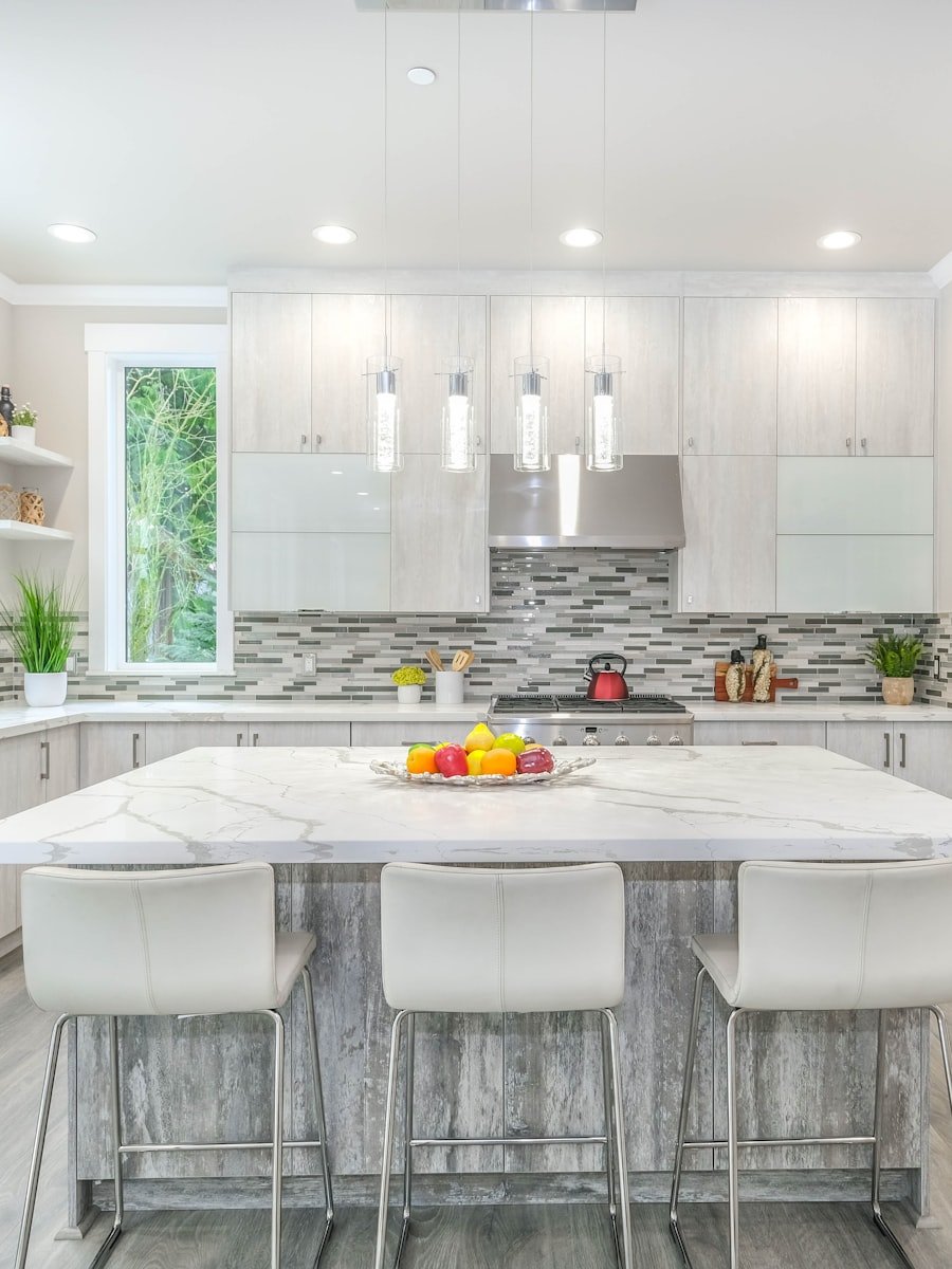 A bright kitchen with an island, stools and fitted cabinetry.
