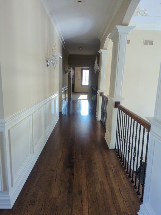 Hallway with panelled wainscoting, dark hardwood floor and staircase.